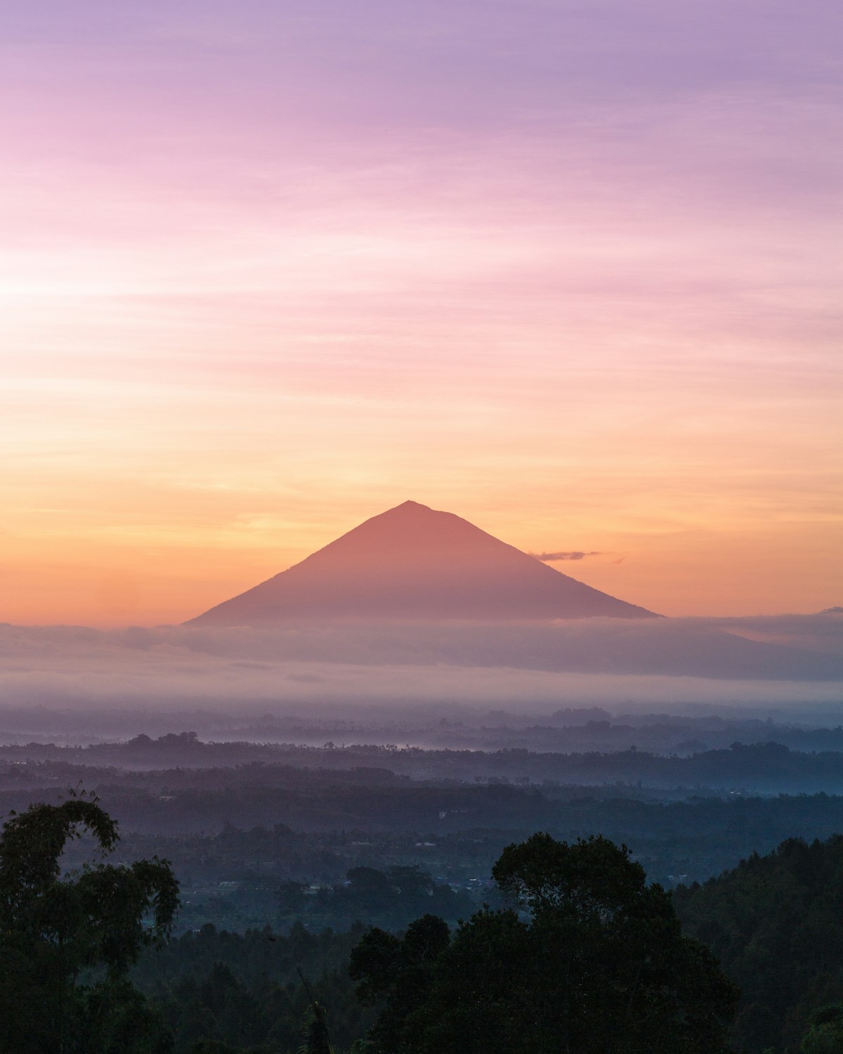 Volcanic mountain silhouette under orange sunrise sky, Mount Batur, Bali, Indonesia