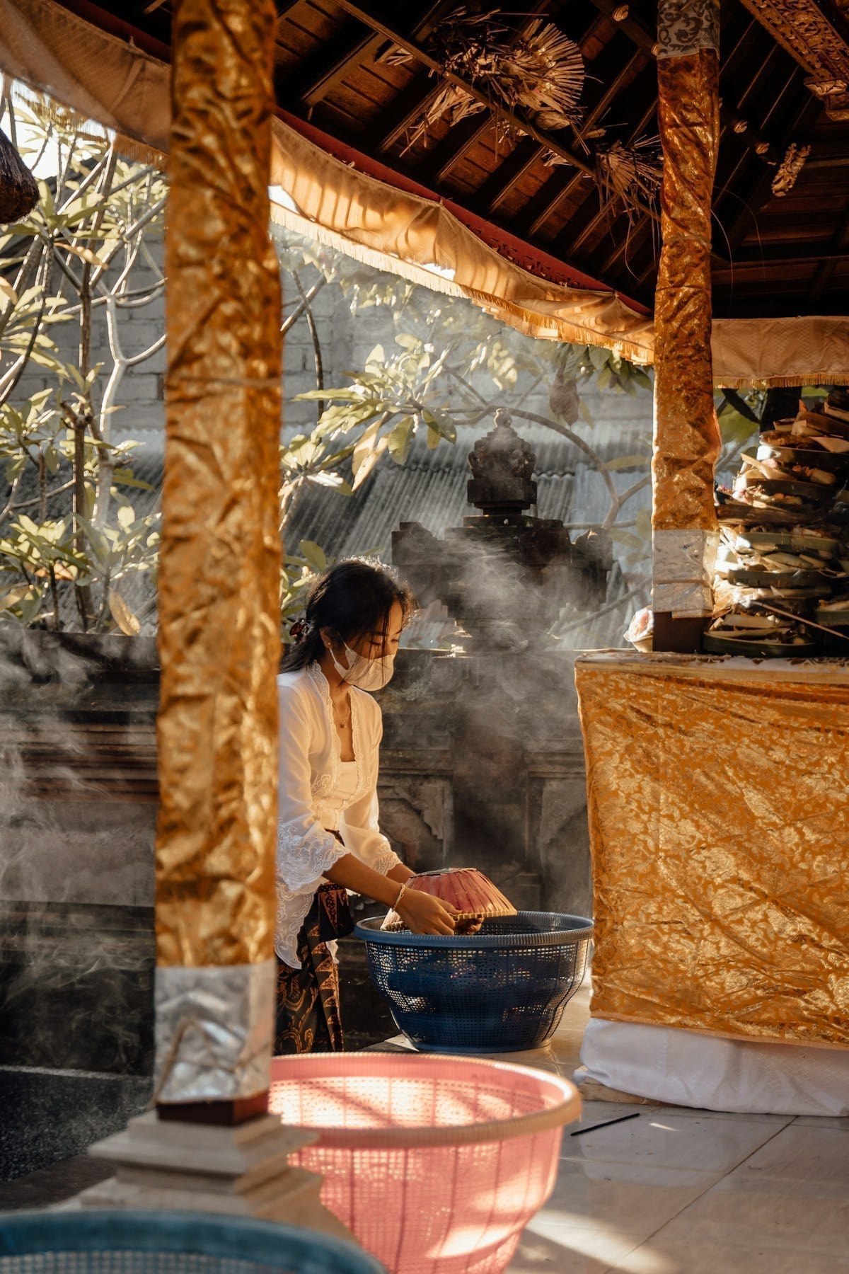 Woman cooking in a large bowl in a traditional Balinese open-air pavilion, Bali, Indonesia