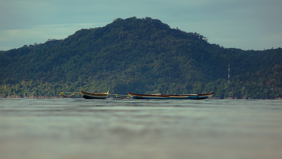 Wooden boat on body of water near mountain, Ambon, Maluku, Indonesia