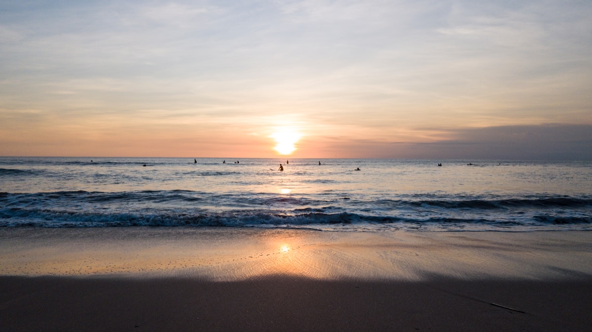 Kuta beach at sunset with surfers in the water, Bali, Indonesia