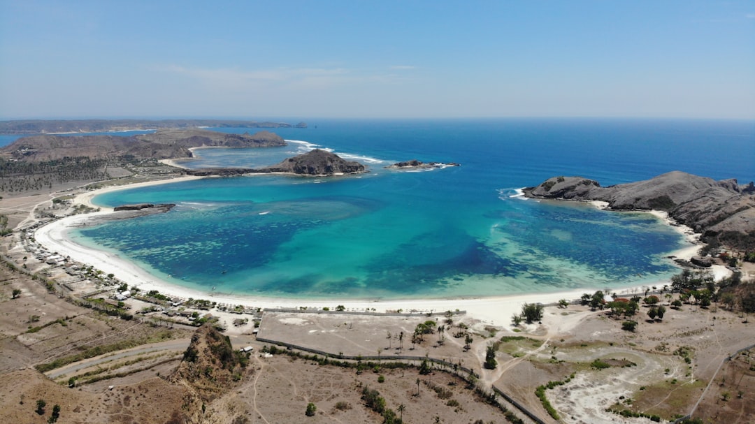 Aerial view of Tanjung Aan beach crescent bay with turquoise water and white sand, Lombok, Indonesia