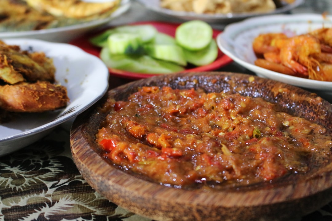 Sambal beberuk with fried tempeh and grilled seafood arranged on a traditional wooden platter in a Lombok warung, Indonesia