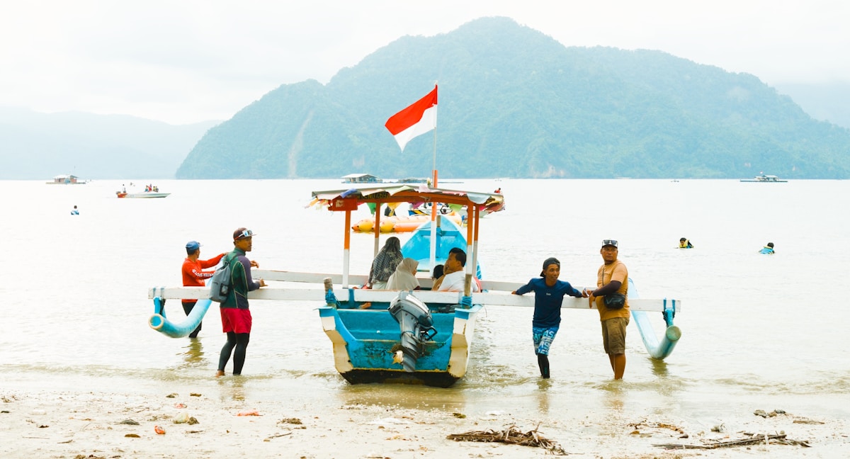 Fishermen pushing a boat ashore with Indonesian flag, East Java, Indonesia