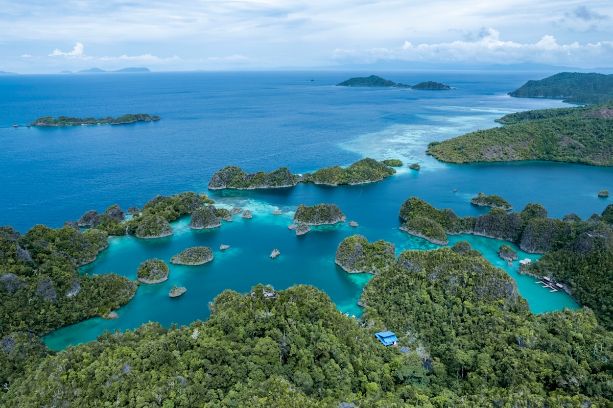 Liveaboard boat moored in calm blue water surrounded by Raja Ampat islands at sunset