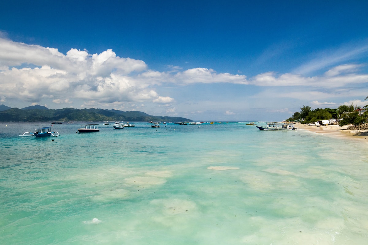 Boats anchored in turquoise water off Gili Trawangan with Lombok mountains in background, Indonesia