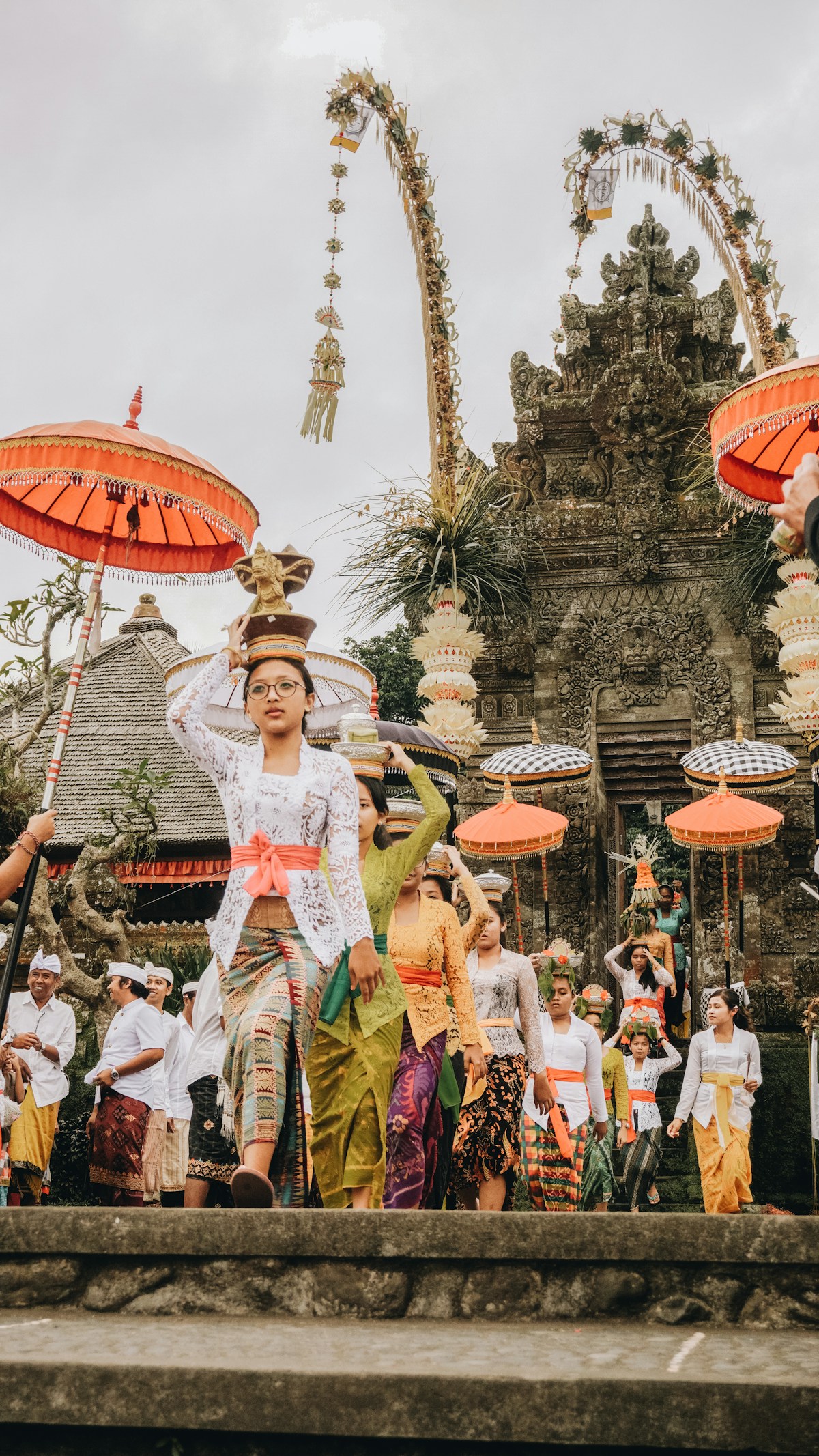 Women in traditional dress with flower pots during ceremony, Penglipuran Village, Bali, Indonesia