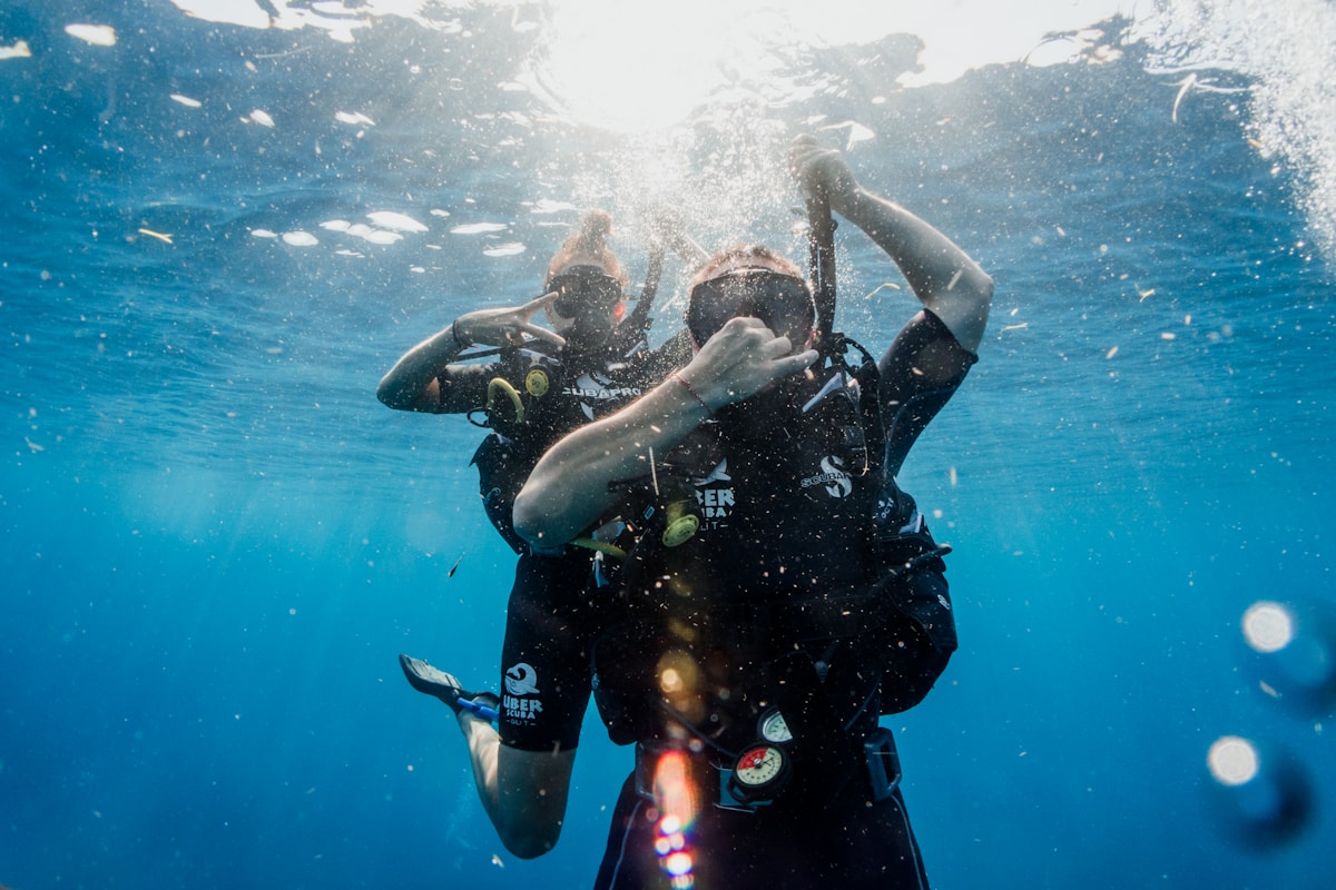 Man in black wetsuit diving in clear water, Indonesia