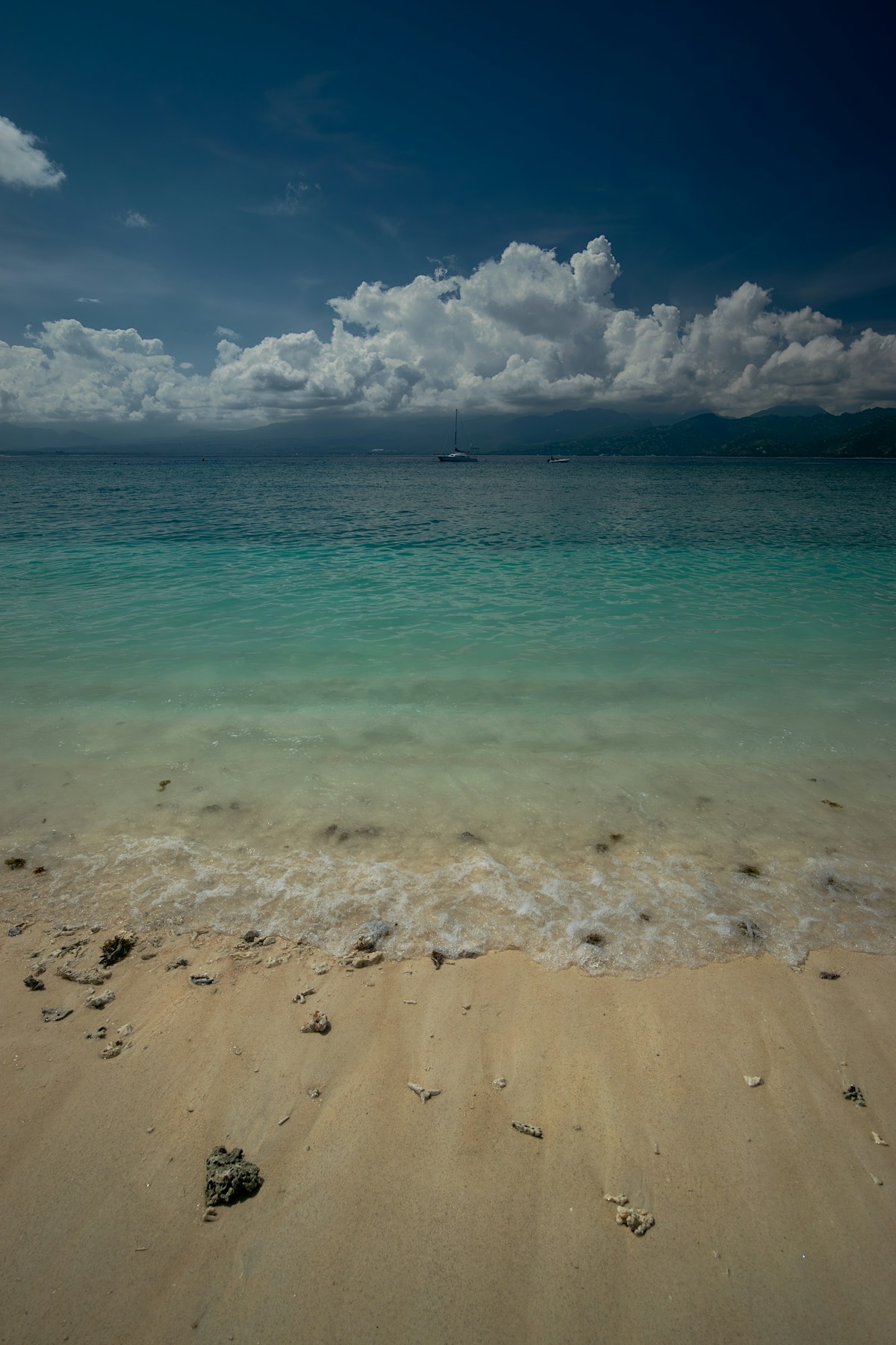 Sandy beach with clear blue water under cloudy sky, Gili Islands, Lombok, Indonesia
