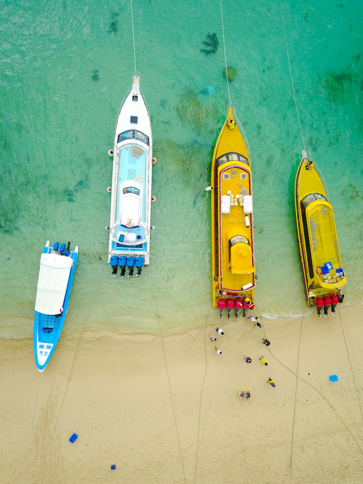 Aerial view of colourful fast boats moored at sandy shoreline with turquoise water, Nusa Lembongan, Bali, Indonesia
