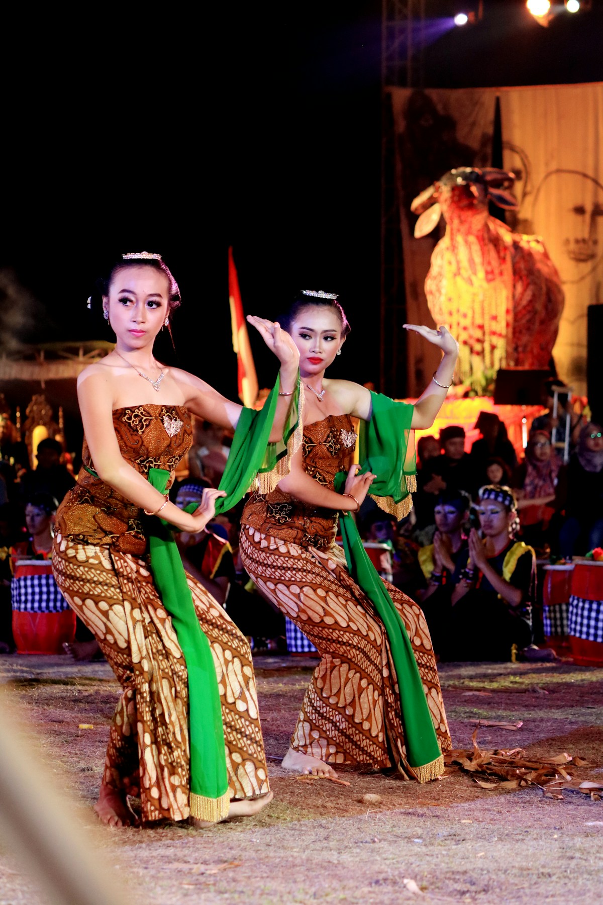 Woman in traditional green and yellow dress dancing at night, East Java, Indonesia