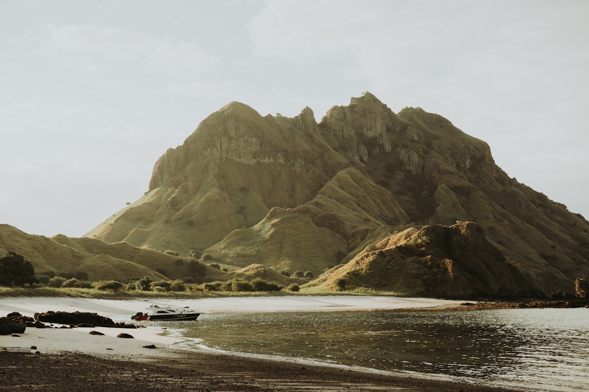 Boat moored on a beach below Padar Island hills, Komodo National Park
