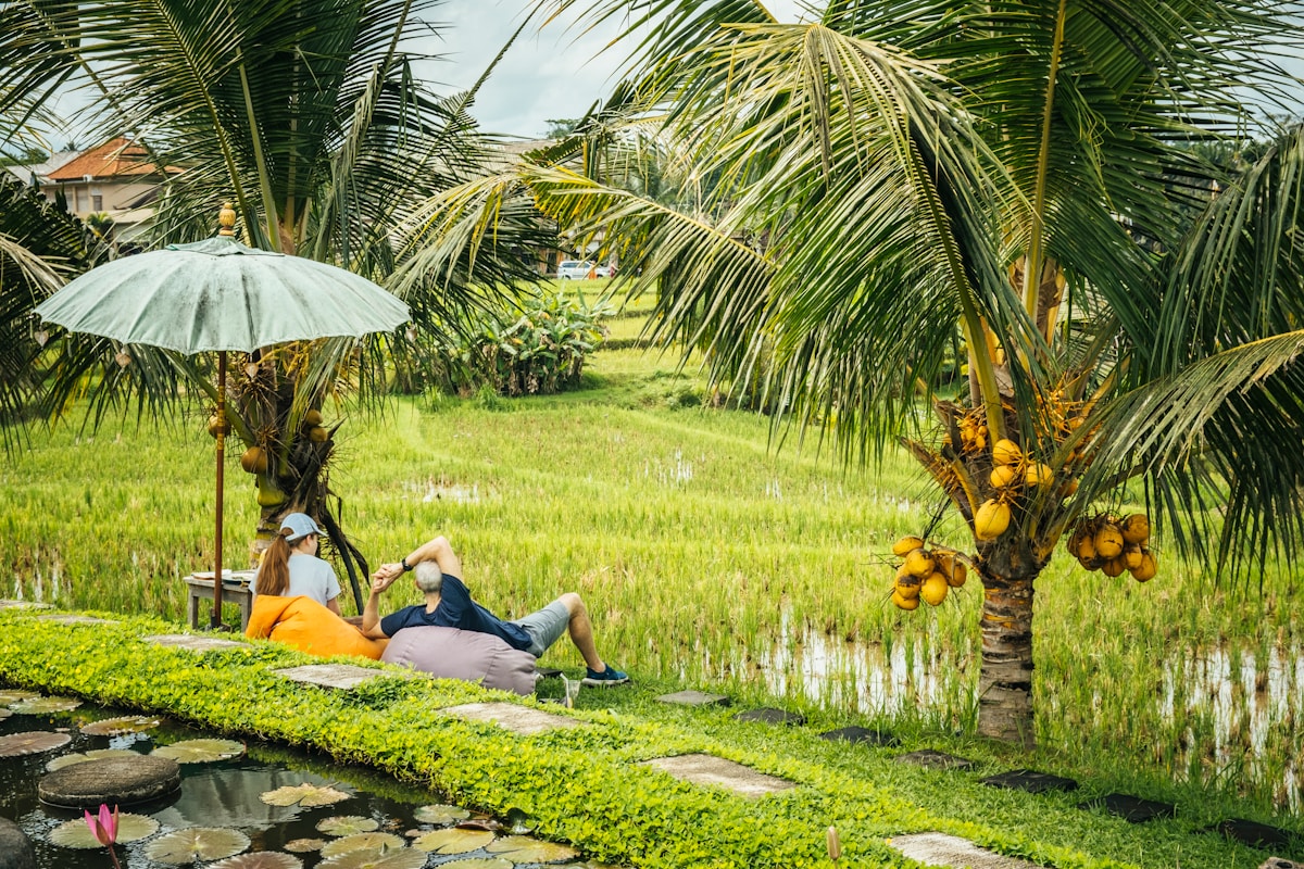 Couple sitting under umbrella in tropical garden, Ubud, Bali, Indonesia