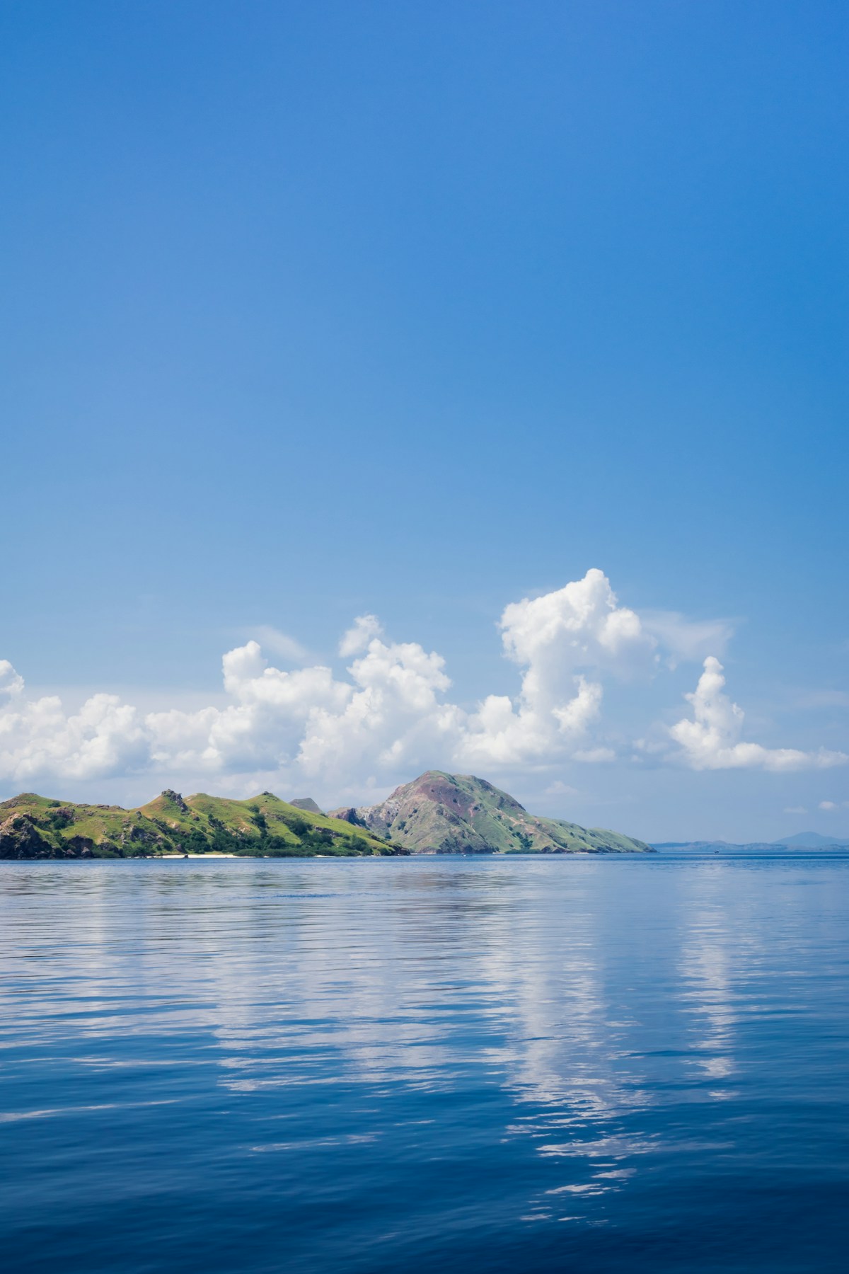 Green island on blue sea under blue sky and white clouds, Indonesia