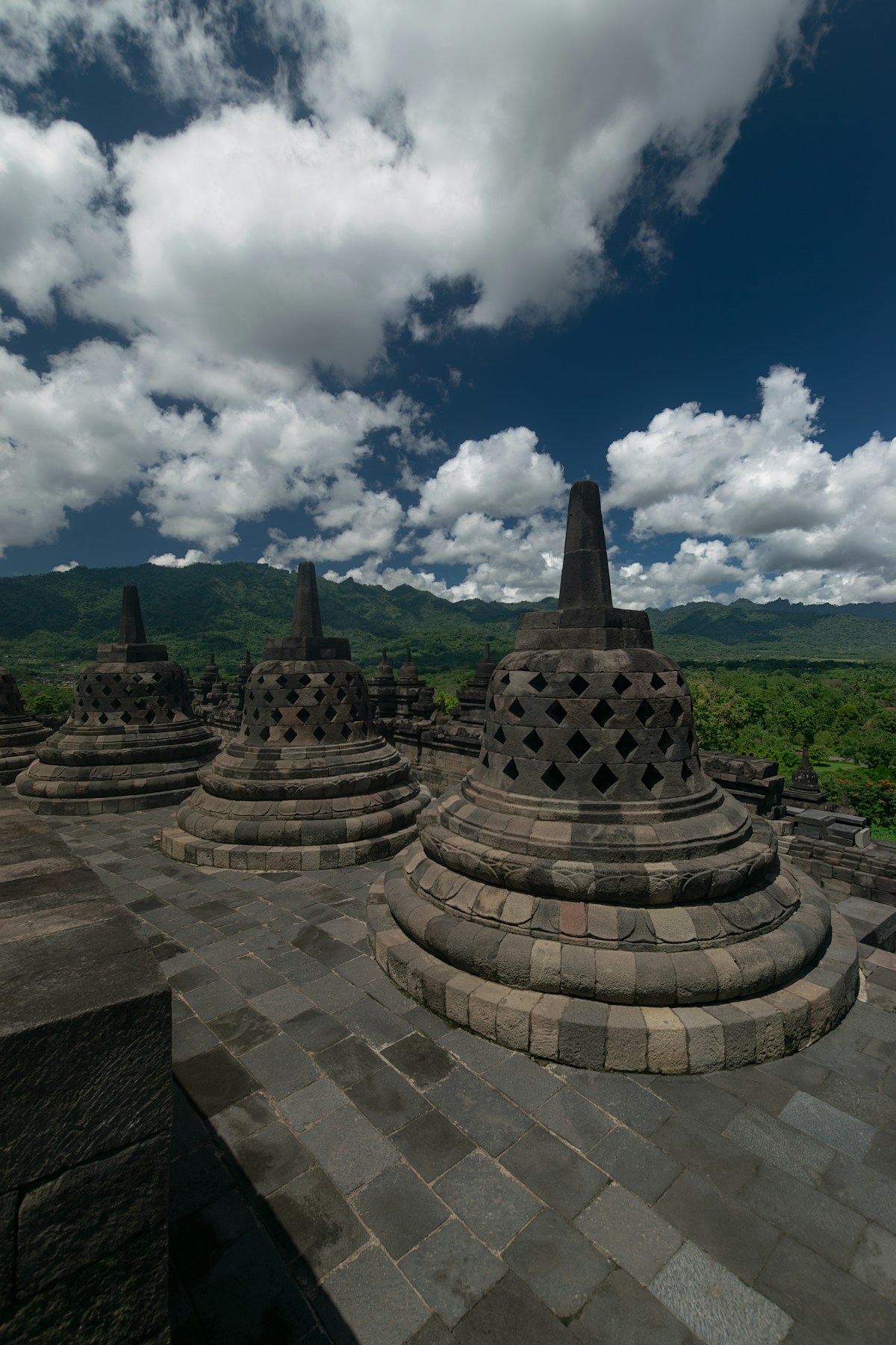 Stone temple structures on a lush green hillside, Yogyakarta, Java, Indonesia