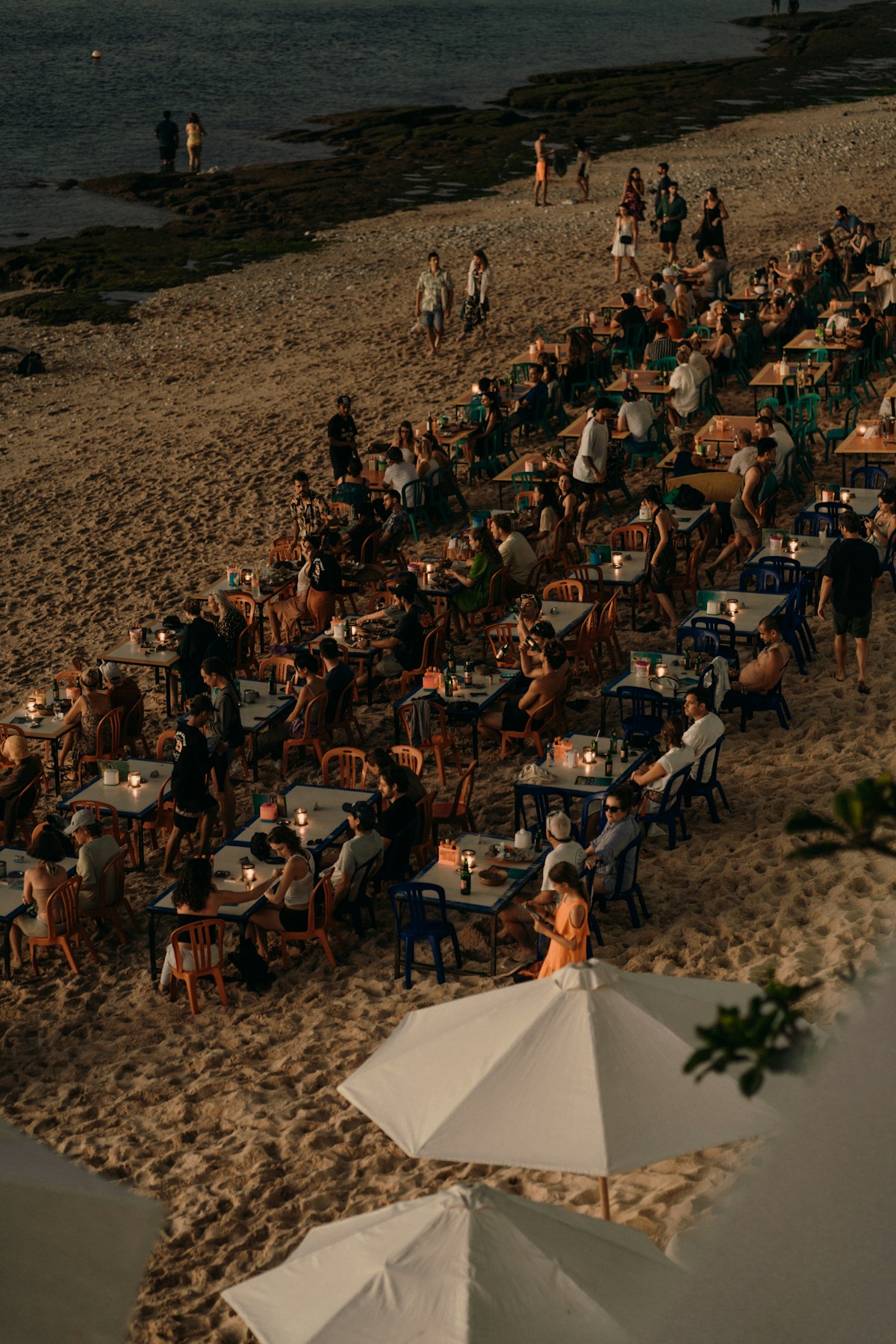 People dining at tables on the beach at sunset, Jimbaran Bay, Bali, Indonesia