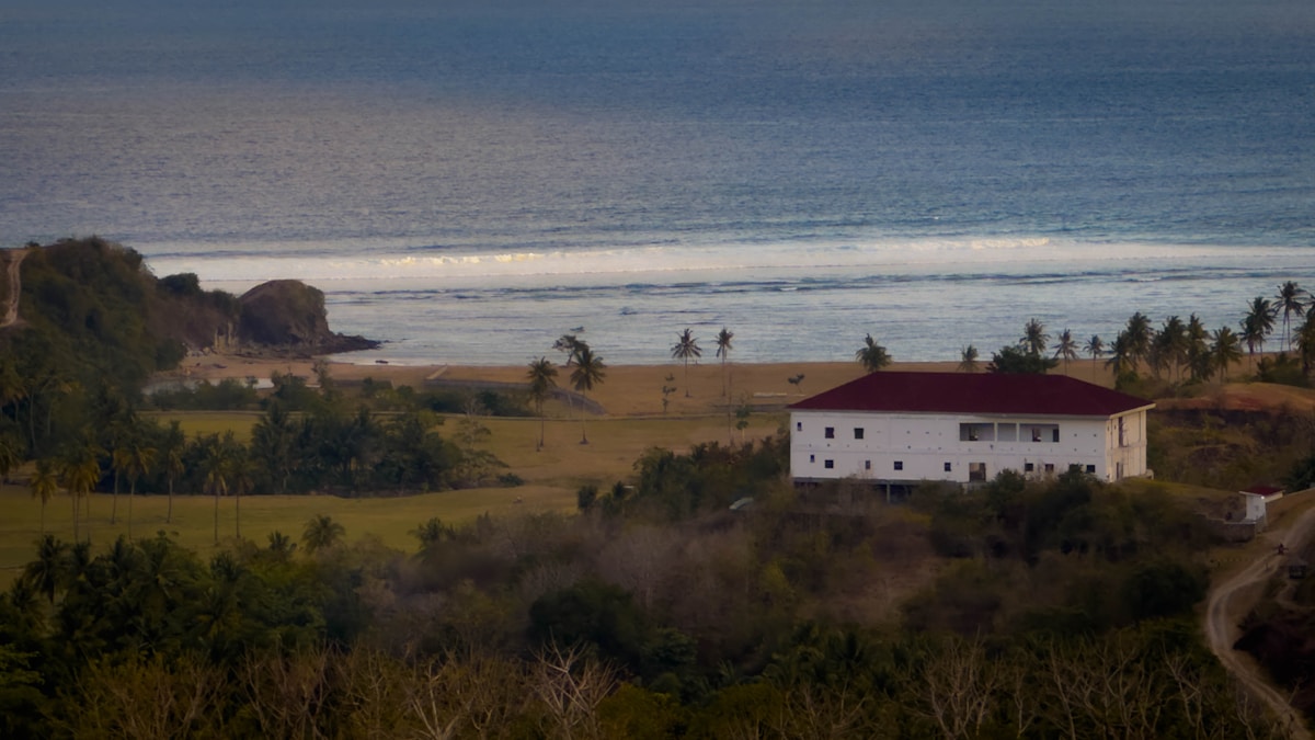 White guesthouse on lush green hillside, Kuta, Central Lombok, Indonesia