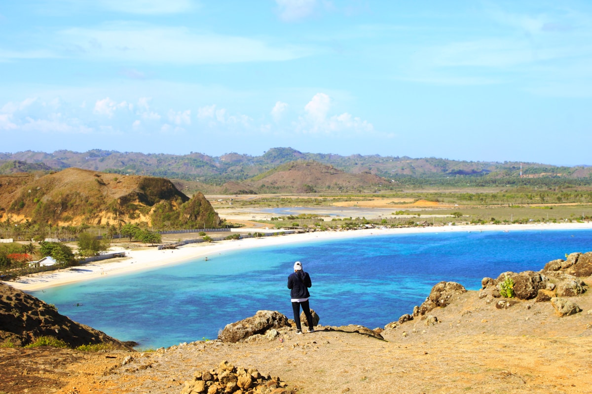 Man on rocky viewpoint at Merese Hills overlooking the bay, Kuta Lombok, Indonesia