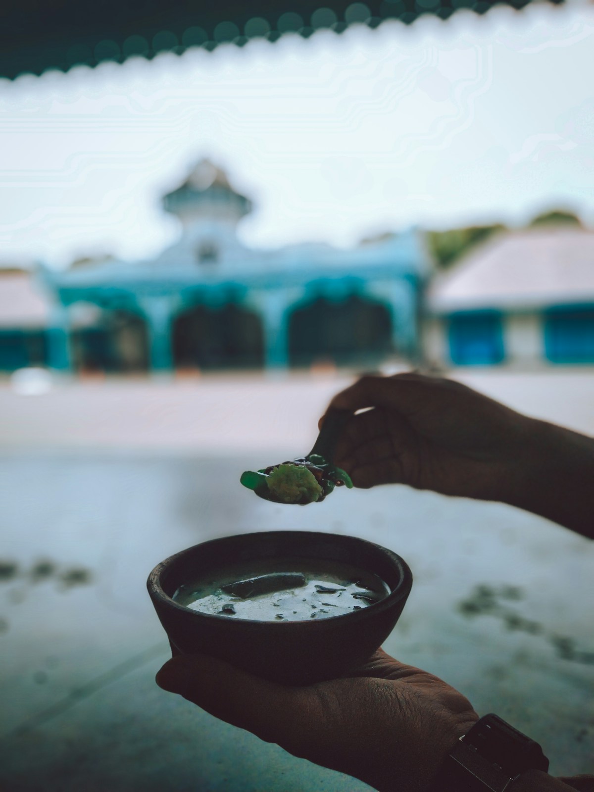 Hand holding bowl of soup with spoon, Indonesia