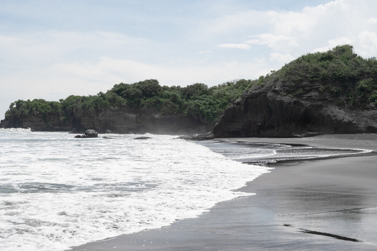 Black sand beach with volcanic rock cliffs, Bali, Indonesia