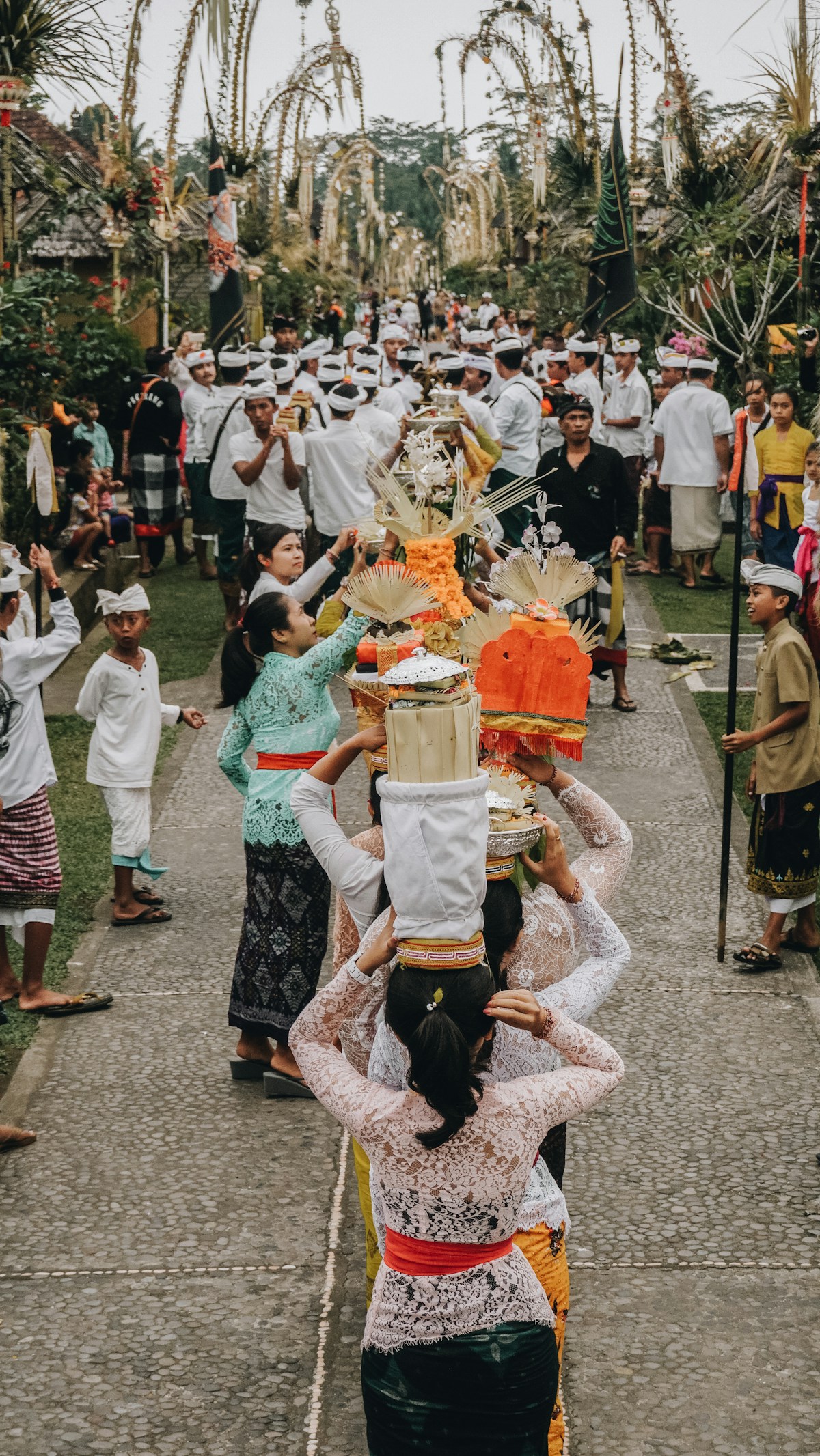 Balinese women carrying offerings in a ceremonial procession through a village, Bali