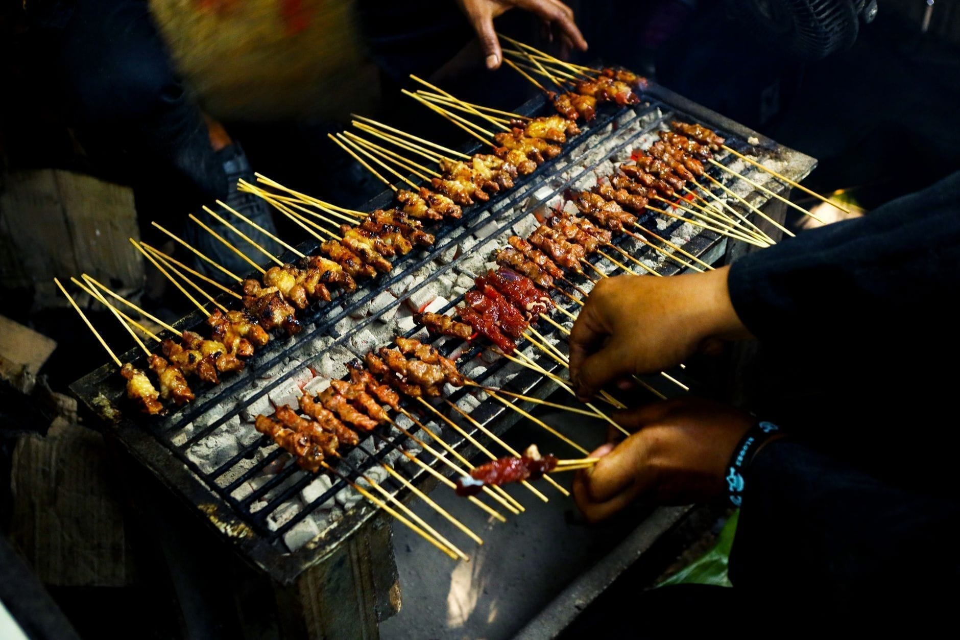 Sate skewers grilling over charcoal at Indonesian night market
