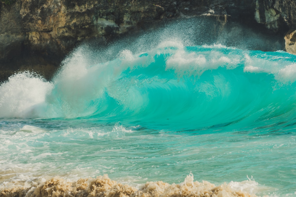 Turquoise wave crashing against limestone cliffs, Kelingking Beach, Nusa Penida, Bali