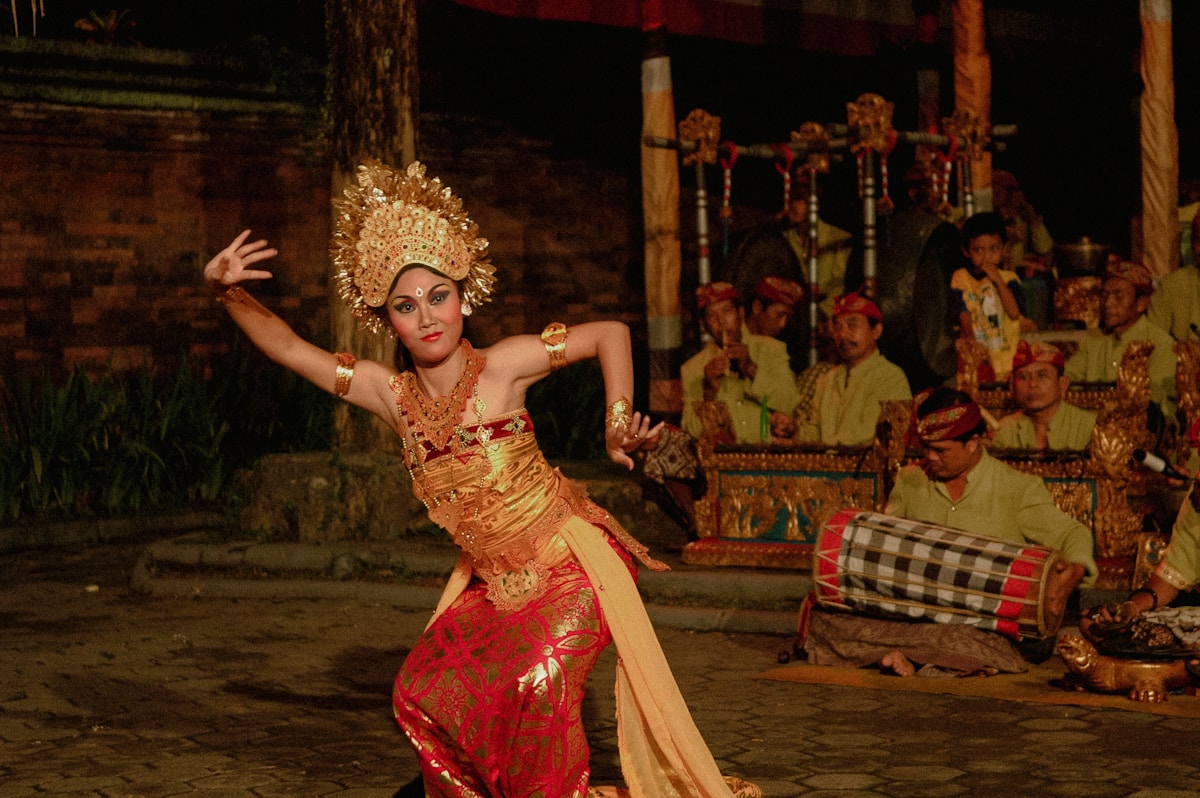 Balinese dancer in elaborate gold costume performs at night in Bali, Indonesia