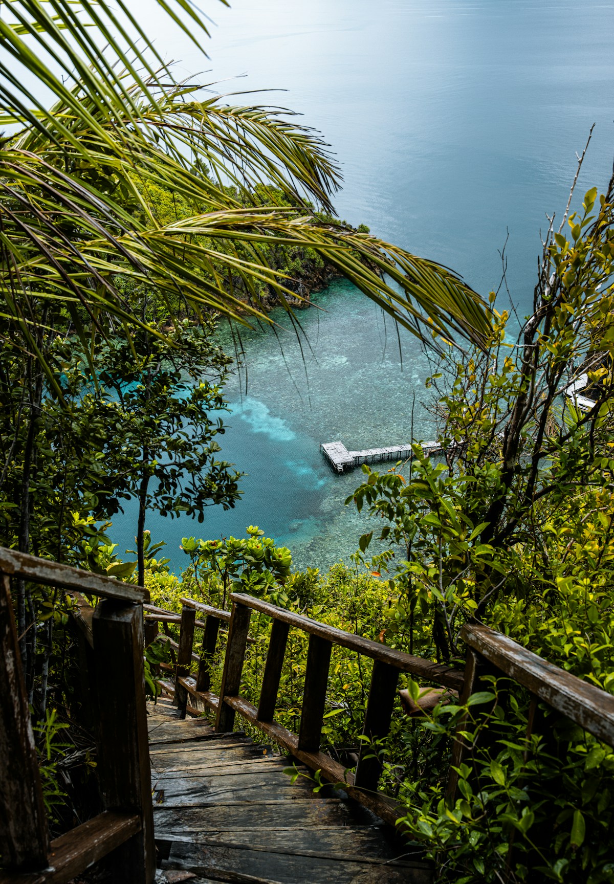 Wooden staircase leading to a tropical beach with boat, Indonesia