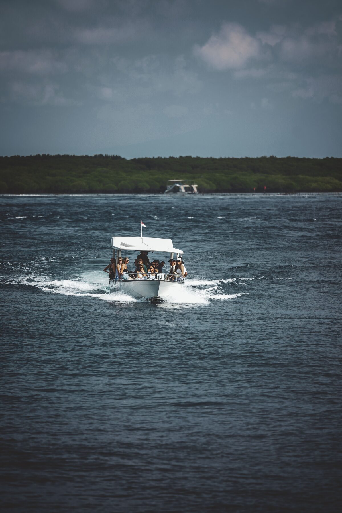 Tour boat with passengers cruising through tropical Bali waters, Indonesia