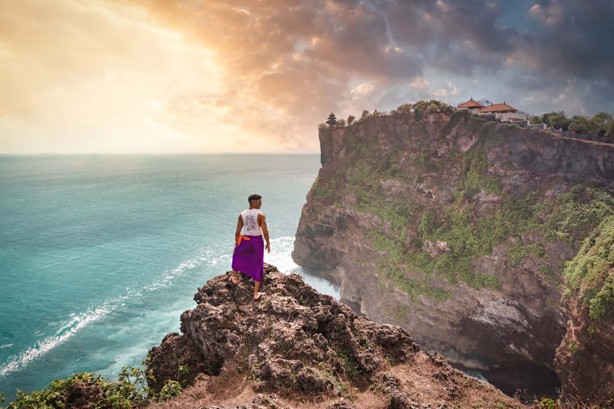 Person standing on a cliff overlooking the ocean, Uluwatu, Bali, Indonesia