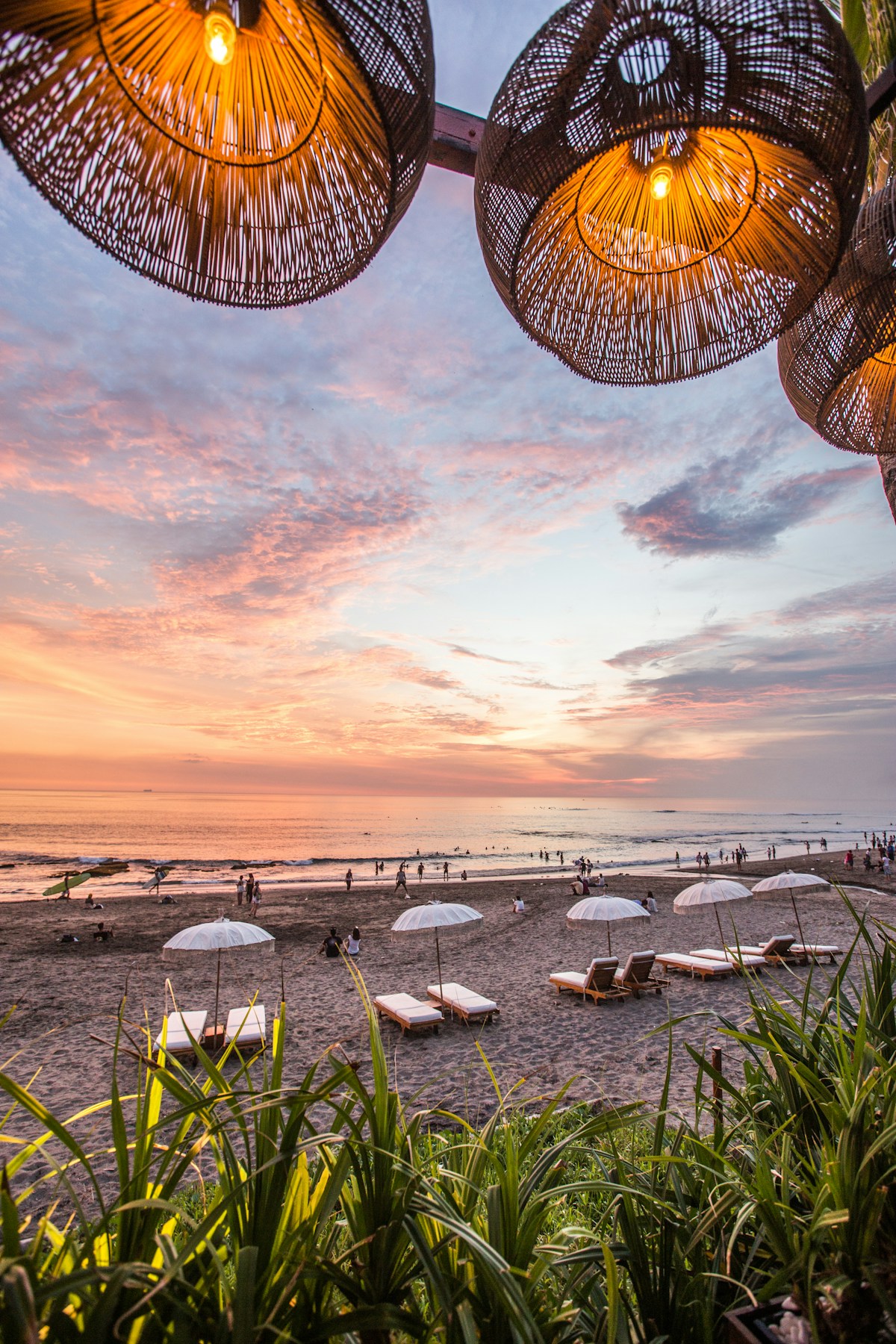 Beach bar with wicker lamps and sun loungers at sunset, Canggu, Bali, Indonesia