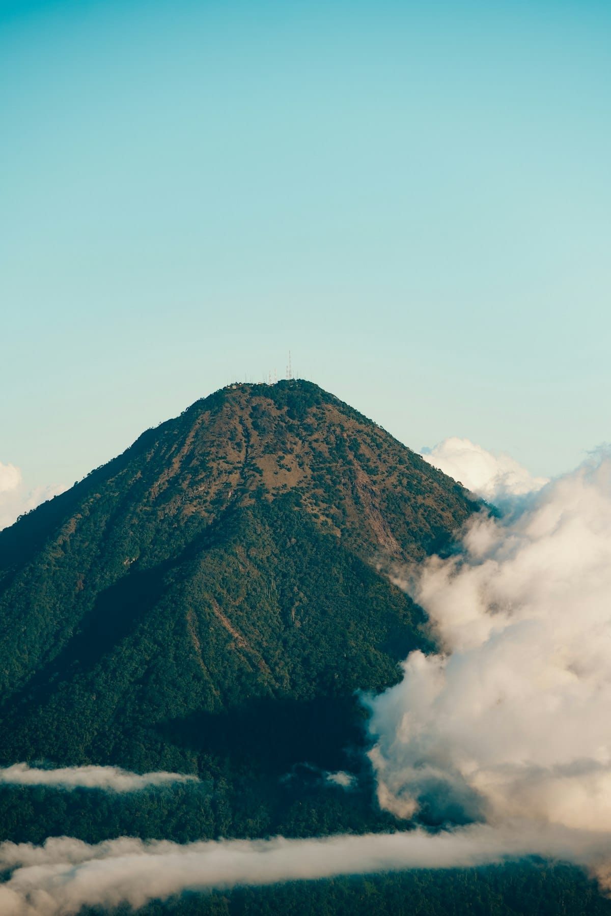 Conical volcanic peak rising above clouds, Flores highlands near Bajawa, Indonesia