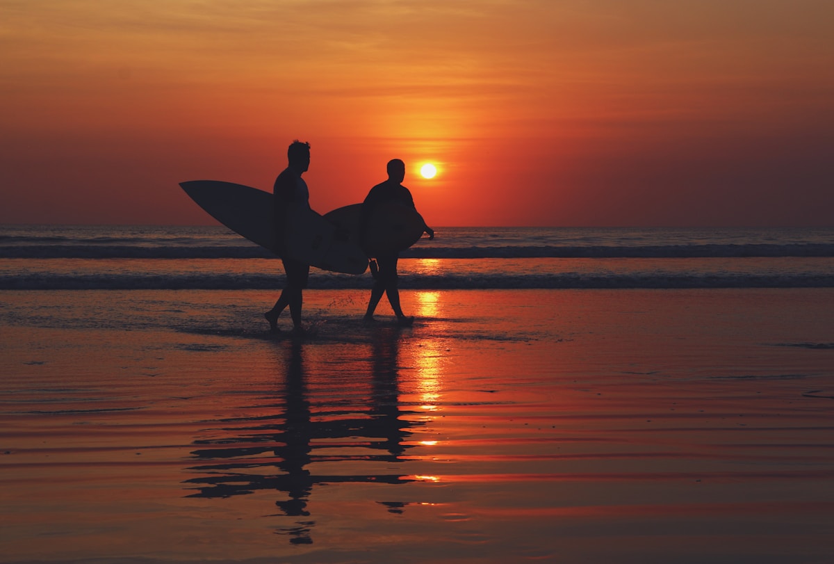 Two surfers walking on Kuta Beach at sunset, Bali, Indonesia