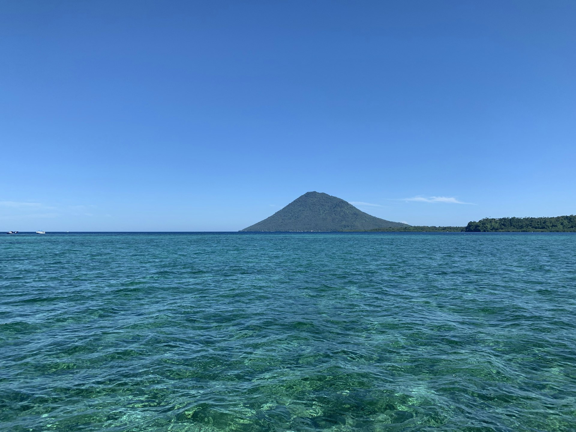 Turquoise sea with volcanic island on the horizon, near Manado, North Sulawesi