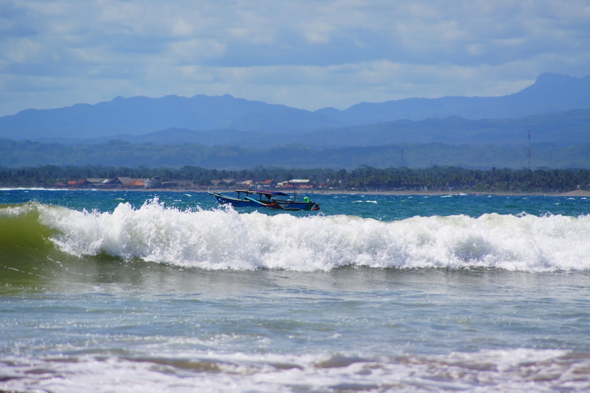 Indonesian fishing boat in rough surf off Pangandaran Beach, West Java, Indonesia