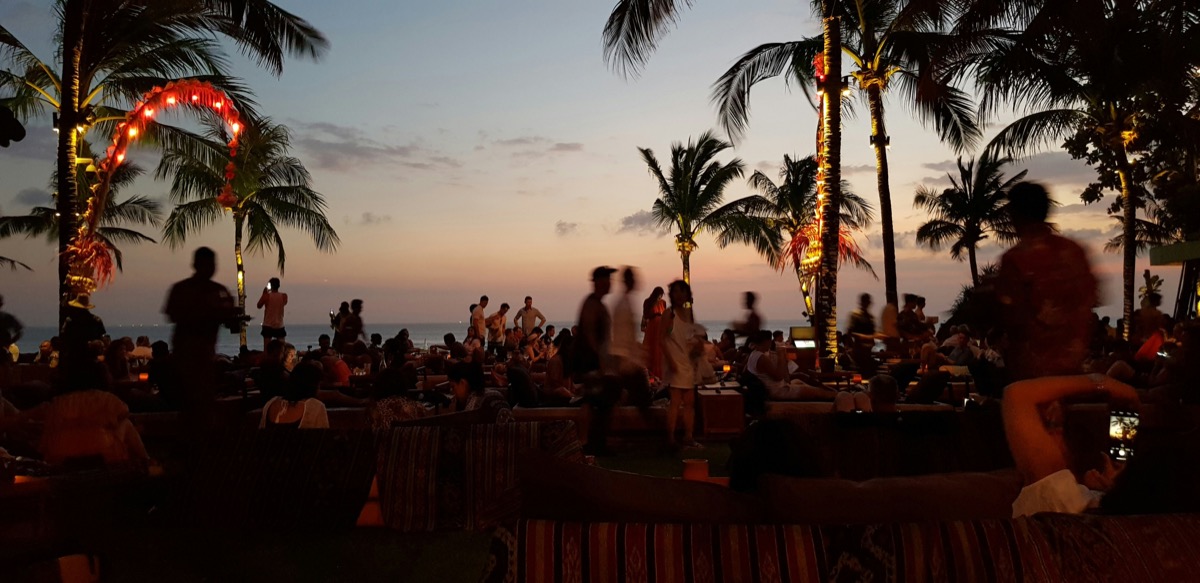 Seminyak beach at golden hour with rows of sun loungers and tropical palms lining the shore