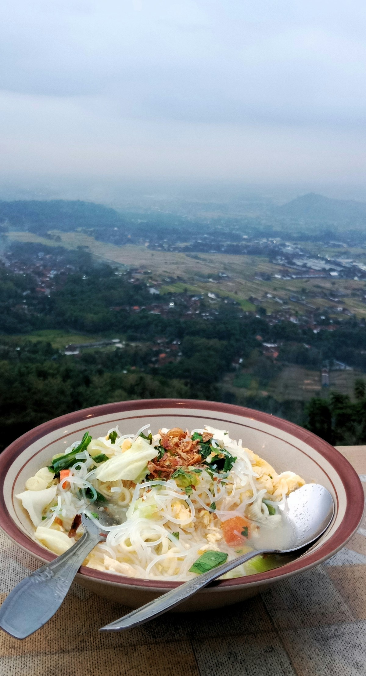 Bowl of mie godhog noodle soup with a view of Yogyakarta valley, Indonesia